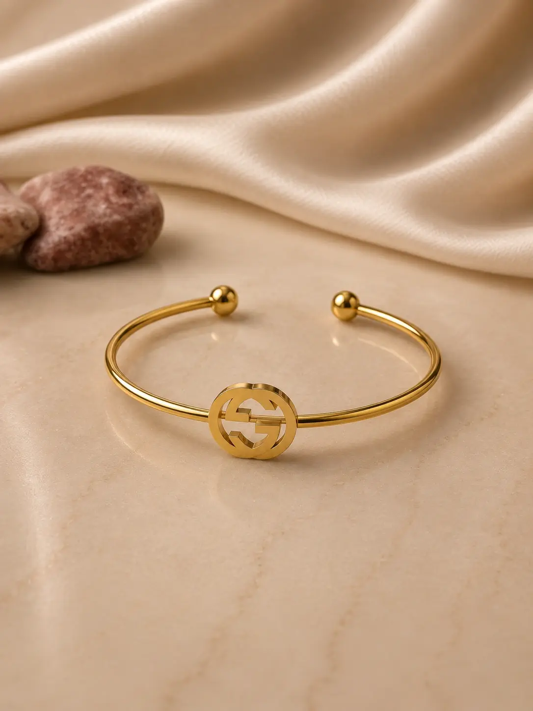 gold tone circular monogram open cuff bracelet with polished ball ends